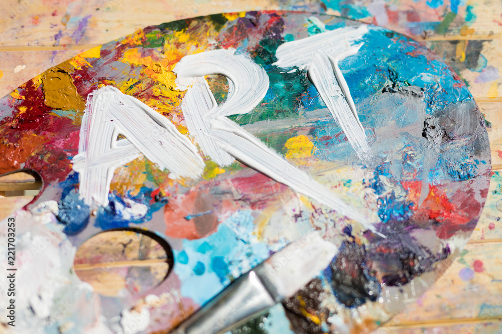 Word art painted with white gouache on colorful palette with paintbrush near by - obrazy, fototapety, plakaty 