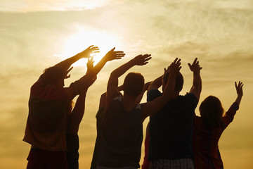 Wall Mural - Stretching arms exercise, back view. Sundown background.