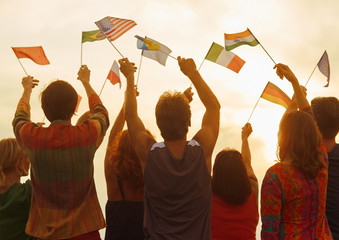 Wall Mural - People holding flags of their country. Crowd of international people. Evening sky background.