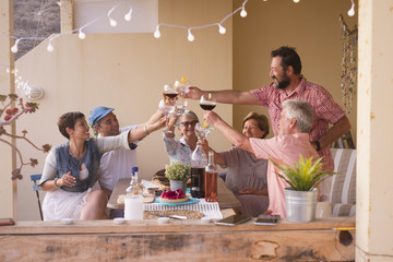 happy group of different ages people celebrating and having fun together in friendship at home or restaurant. cheering and toasting with cocktails and alchool. smile and enjoy the party with adult