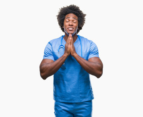 Canvas Print - Afro american surgeon doctor man over isolated background praying with hands together asking for forgiveness smiling confident.