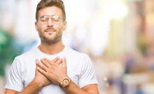 Young Handsome Man Wearing Glasses Over Isolated Background Smiling With Hands On Chest With Closed Eyes And Grateful Gesture On Face. Health Concept.