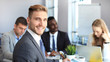 © ty - Businessman with colleagues in the background in office.