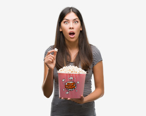 Poster - Young beautiful hispanic eating popcorn scared in shock with a surprise face, afraid and excited with fear expression