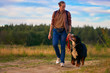 Dog walking in nature. the guy is walking with a big dog on the road outside the city in the field