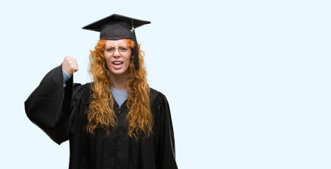 Wall Mural - Young redhead student woman wearing graduated uniform annoyed and frustrated shouting with anger, crazy and yelling with raised hand, anger concept