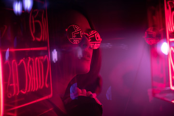 Long hair girl with sunglasses and leather jacket looking at neon lights