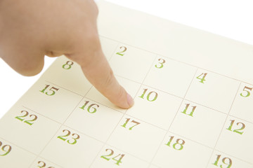 female's finger showing date in a calendar on white background. number in the calendar