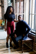 © sofiko14 - young African American woman and man sitting at a brick wall with a window.