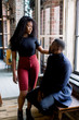 © sofiko14 - young African American woman and man sitting at a brick wall with a window.