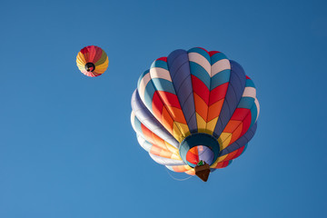 Two hot air balloons flying high in the blue sky