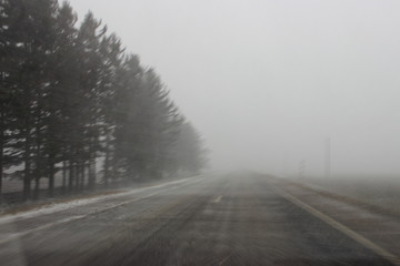 Snowstorm, view from windshield on first snow - european two way country asphalt road with limited visibility, difficult car driving, emergency, country landscape