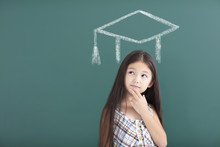 Girl In Graduation Cap With Thinking Gesture Before  Chalkboard