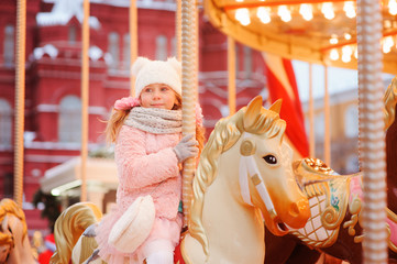 Wall Mural - happy kid girl in amusement park on Christmas and New Year Holidays. Moscow Red Square on background