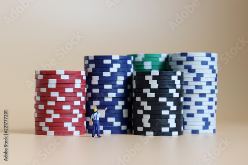 фотография Miniature man pointing to a pile of casinos chips.