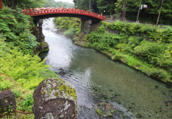 closeup of a rock cover by lichens beside the creek with red old bridge and natural background.