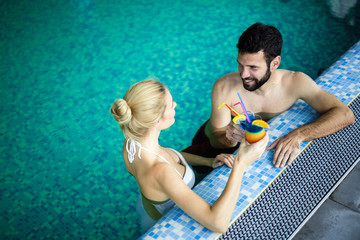 Wall Mural - Happy attractive couple relaxing in swimming pool