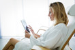 © NDABCREATIVITY - Beautiful woman relaxing and using tablet in spa