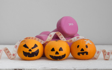 Canvas Print - Halloween Festical with Fitness, Exercise, Working out, weight and dieting, healthy lifestyle background concept. Fresh Orange with Head Pumpkins  haunted spooky face with dumbbells and tape measure