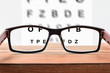 Glasses on table and alphabet letter front view
