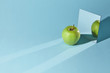 © artjazz - The apple is green, a square mirror on a blue background, a reflection of an apple and from shadows in a mirror.