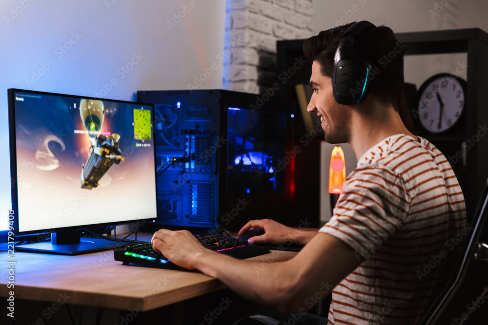 Portrait of young gamer man playing video games on computer, wearing ...