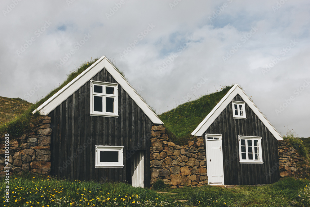 Black farmhouse in Skaftafell National Park under cloudy sky in Iceland - obrazy, fototapety, plakaty 
