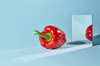 Sweet red pepper, a square mirror on a blue background, a reflection of an pepper and from shadow in a mirror.