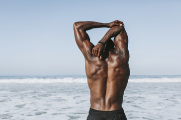 Wall Mural - Fit man stretching at the beach