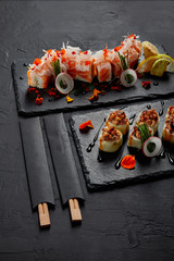 Wall Mural - delicious fresh sushi rolls on slate boards and chopsticks