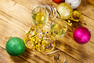 Two glasses of champagne and festive Christmas decorations on wooden table. Top view. Christmas and New Year celebration