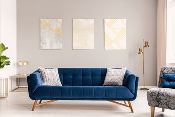 Wall Mural - Elegant living room interior with a comfortable big blue velvet sofa and gold decorations. Real photo.