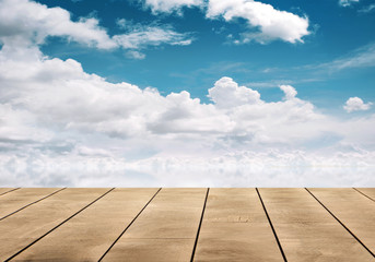 Wall Mural - wooden table top with blue sky reflective on water
