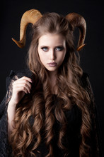 Portrait Of An Attractive Demon Woman With Horns And Curly Hair, Studio Shot For Halloween