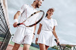 Enjoying spending time on the court. Beautiful young couple walking on the tennis court with smile.