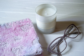 Wall Mural - The closed pink notepad, white candle and glasses on a white wooden table. Work place still life.