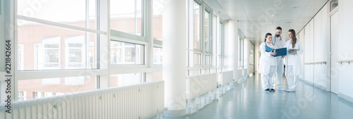 Fotografía Drei Ärzte im Flur von Krankenhaus unterhalten sich kurz