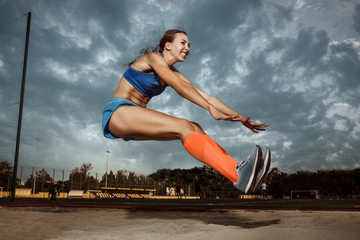 Female athlete performing a long jump during a competition at stadium. The jump, athlete, action, motion, sport, success, championship concept