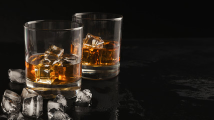 Wall Mural - Two glasses of whiskey and ice on black background