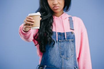 Wall Mural - partial view of young african american woman showing disposable coffee cup isolated on blue background