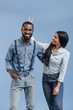 © LIGHTFIELD STUDIOS - smiling african american girlfriend showing two fingers above boyfriend head isolated on blue