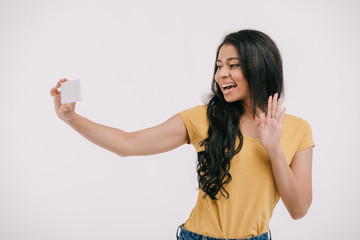 Wall Mural - attractive african american girl waving hand during video call on smartphone isolated on white