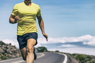 Runner athlete training on outdoor run with wearable tech smart watch working out cardio in intense exercise. Fit and healthy man.