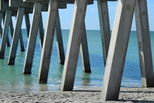 Underneath Fishing Pier Showing Concrete Pillars With Blue Green Water On The Ocean
