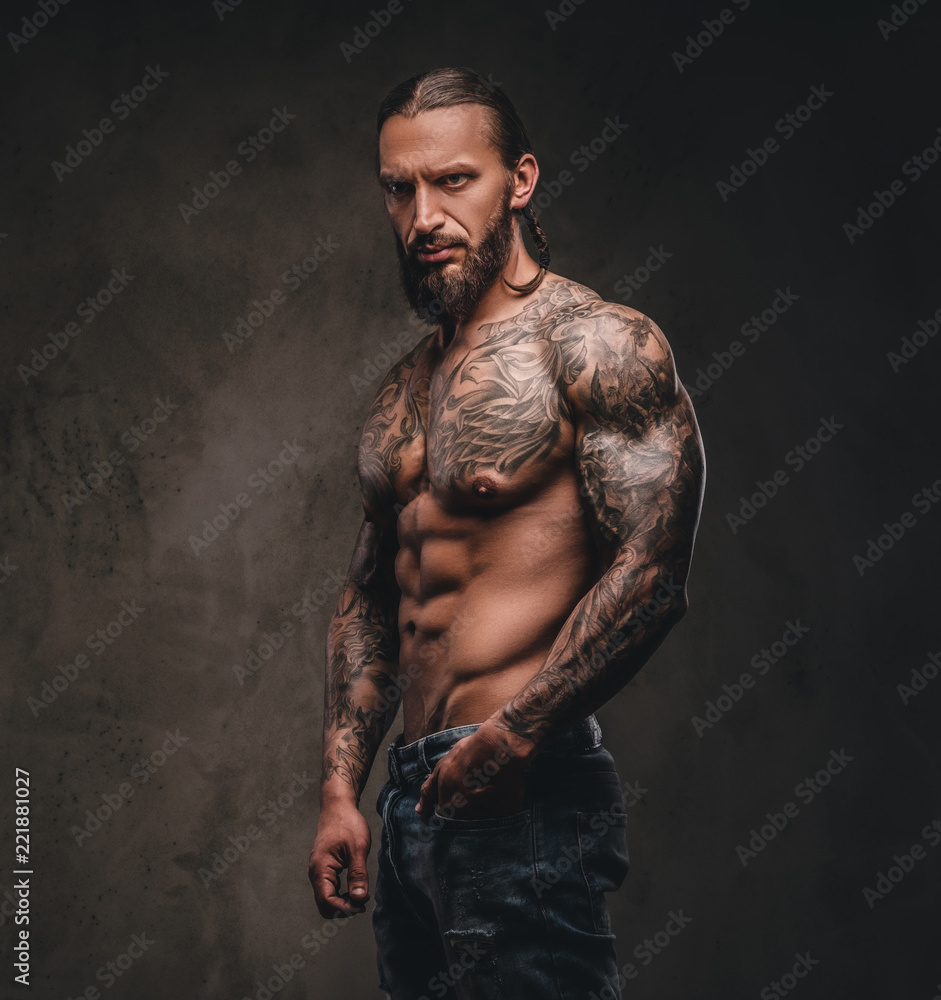 Portrait of a shirtless bearded tattooed male posing with hand in ...
