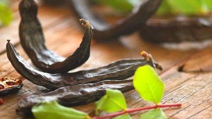 Sticker - Carob. Healthy organic sweet carob pods with seeds and leaves on a wooden table. Healthy eating, food background. Slow motion. 3840X2160 4K UHD video footage