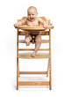 Happy cute baby girl sitting in high chair over white