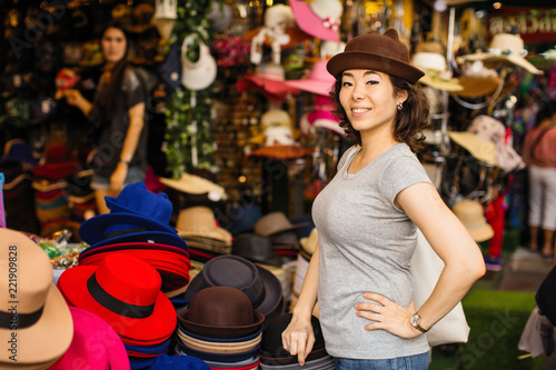 Foto  Cute mixed race woman trying on a hat in the store..