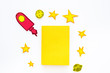 © 9dreamstudio - Literature for children. Fantactic, fiction story. Book with blank cover near cutout of rocket, stars, moon on white background top view mockup copy space