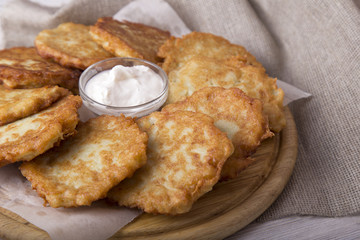 Wall Mural - Potato pancakes with sour cream. Homemade draniki on wooden board